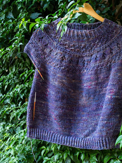 A hand knitted sweater hanged on a bouganvillea plant