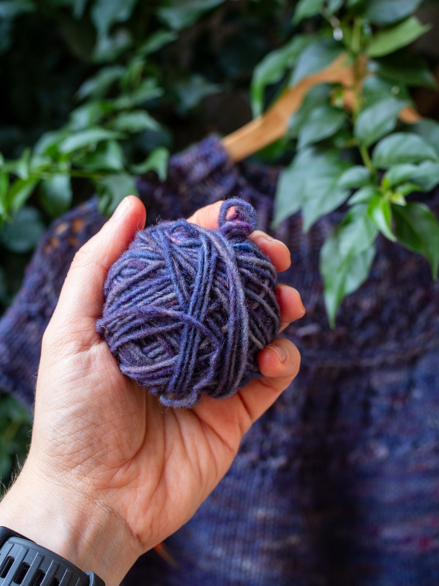 a hand holding a blue ball of yarn