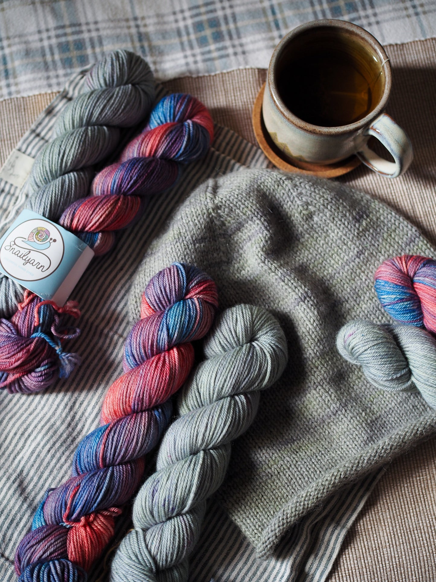 Colorful yarn skeins and a cup of coffee on a textured surface